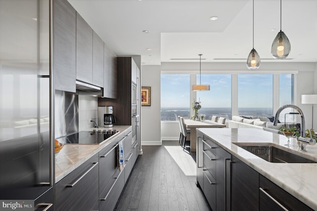 kitchen featuring sink, light stone countertops, hanging light fixtures, black electric stovetop, and dark hardwood / wood-style flooring