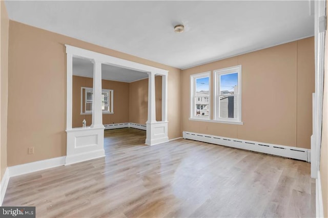 spare room featuring light hardwood / wood-style floors, ornate columns, and a baseboard heating unit