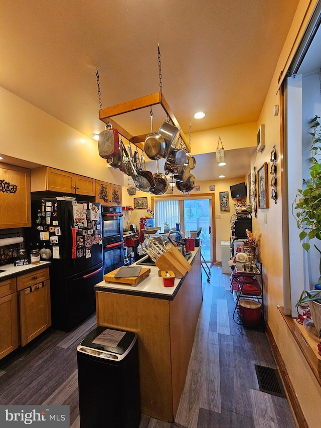 kitchen with dark hardwood / wood-style floors, a kitchen island, and black appliances