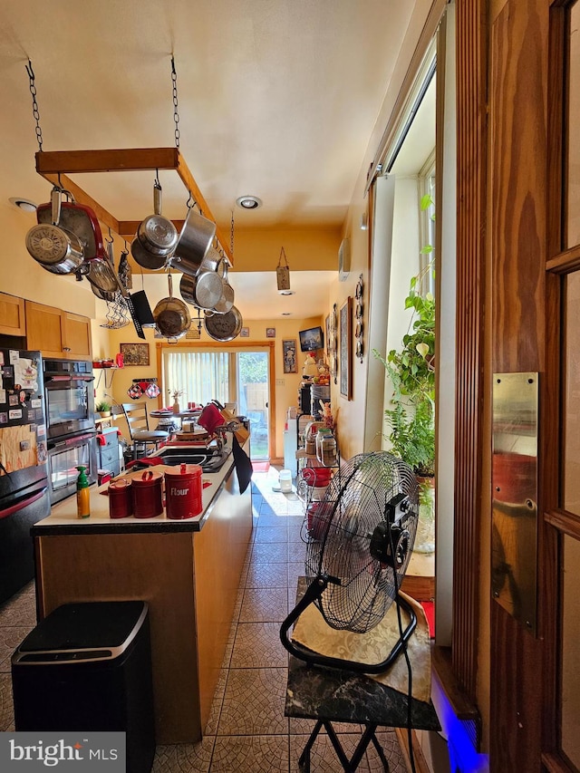 kitchen with a center island, dark tile patterned floors, and black appliances