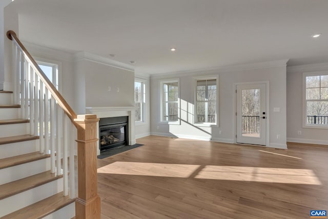 unfurnished living room featuring ornamental molding and light wood-type flooring