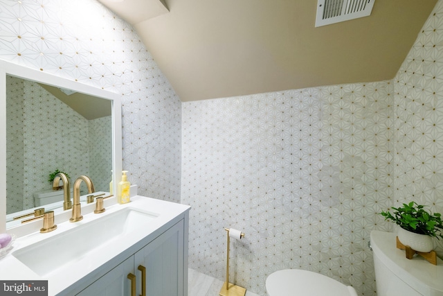 bathroom with tile walls, vanity, toilet, and vaulted ceiling