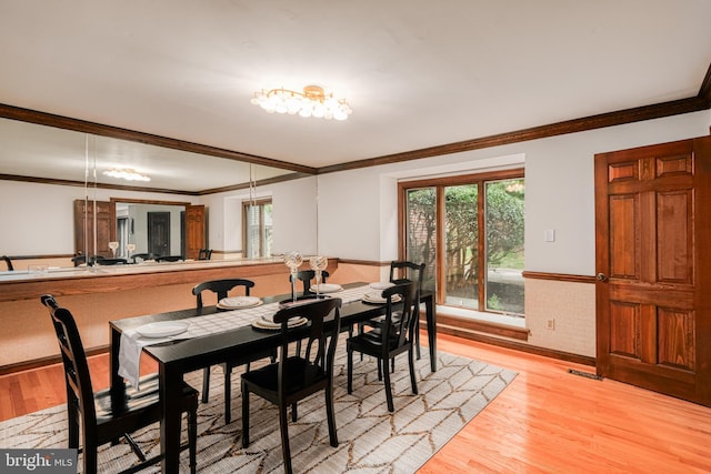 dining room with light wood-type flooring and crown molding