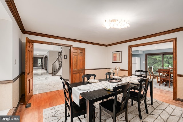 dining area featuring light hardwood / wood-style floors and crown molding