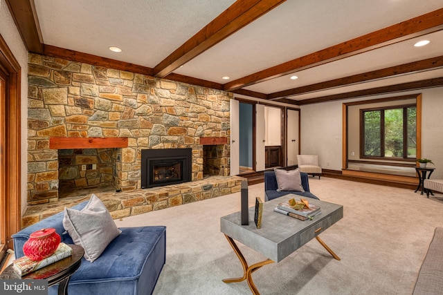 living room with a fireplace, beamed ceiling, a textured ceiling, and carpet flooring