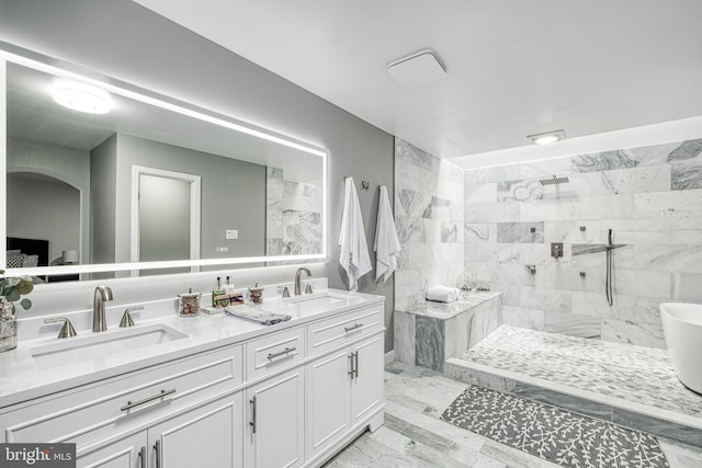 bathroom with tiled shower and vanity