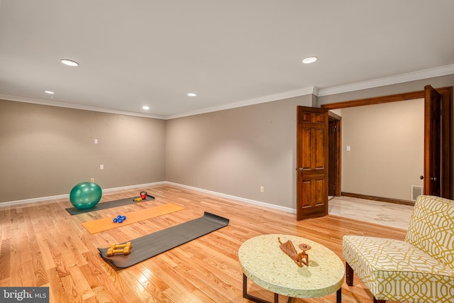 workout area with light wood-type flooring and crown molding