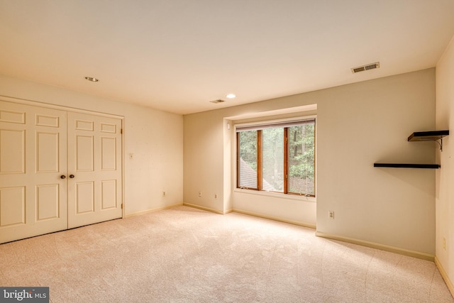 unfurnished bedroom featuring light colored carpet and a closet