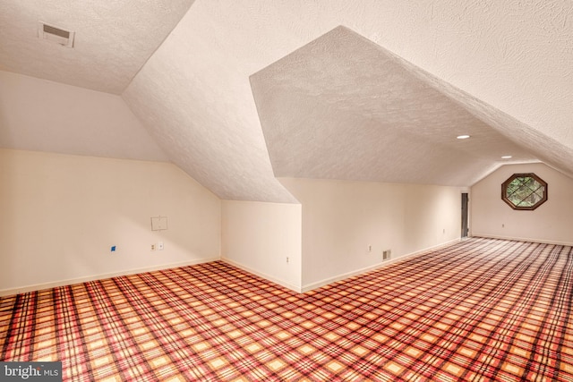 additional living space featuring carpet, a textured ceiling, and vaulted ceiling