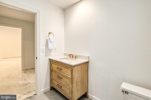 bathroom with toilet, vanity, and tile patterned floors