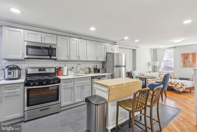 kitchen with hardwood / wood-style floors, gray cabinetry, sink, and appliances with stainless steel finishes