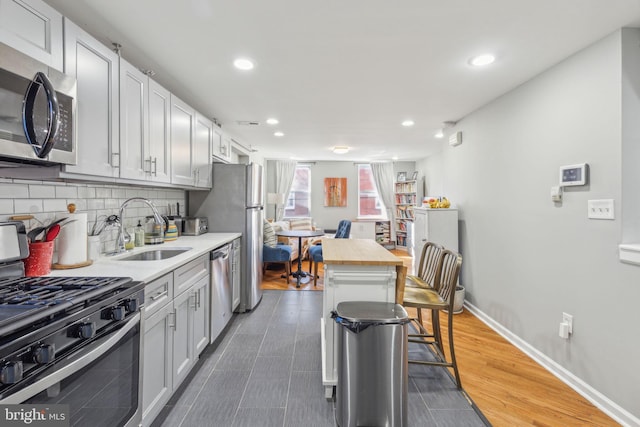 kitchen featuring a center island, sink, appliances with stainless steel finishes, butcher block countertops, and a kitchen bar