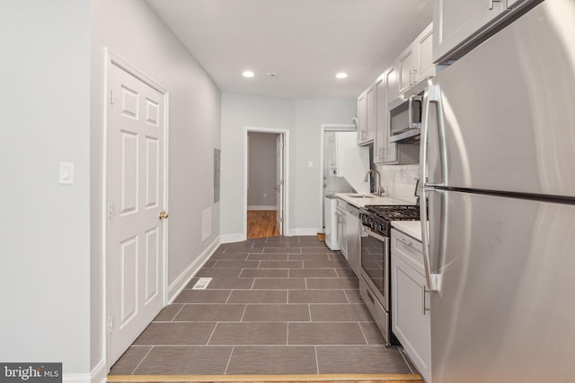 kitchen with decorative backsplash, stainless steel appliances, dark wood-type flooring, sink, and white cabinetry