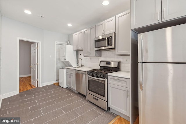 kitchen with white cabinetry, sink, dark wood-type flooring, stainless steel appliances, and tasteful backsplash