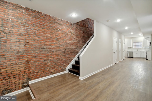 stairs featuring hardwood / wood-style floors and brick wall