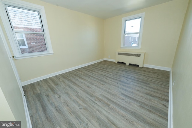 empty room featuring radiator heating unit and light hardwood / wood-style flooring