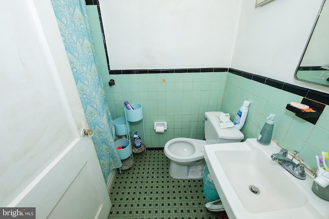 bathroom with toilet, tile walls, and sink