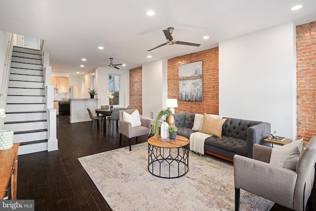 living room featuring dark hardwood / wood-style floors, ceiling fan, and brick wall