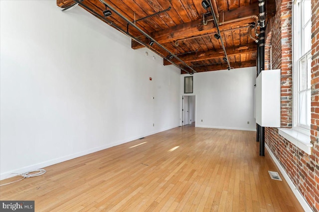 interior space with wooden ceiling, beamed ceiling, brick wall, and light hardwood / wood-style floors