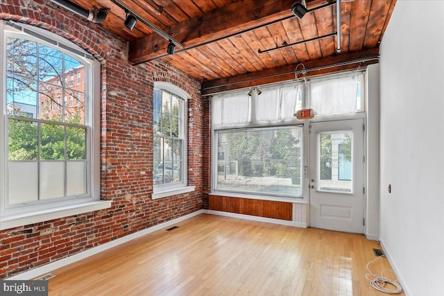 unfurnished sunroom with beam ceiling, a wealth of natural light, and wooden ceiling