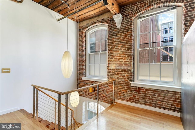 interior space featuring light wood-type flooring, wood ceiling, and brick wall