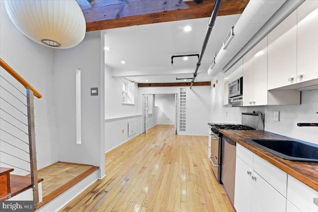 kitchen with butcher block countertops, light hardwood / wood-style floors, and white cabinetry