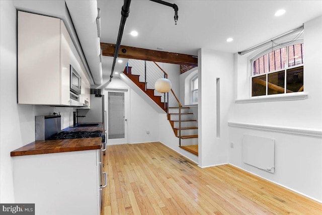 kitchen with butcher block countertops, white cabinets, white gas range, and light hardwood / wood-style flooring