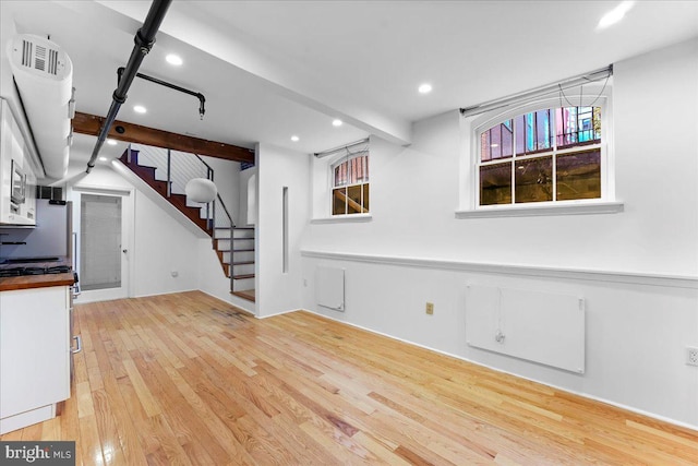 unfurnished living room with light hardwood / wood-style flooring and beamed ceiling