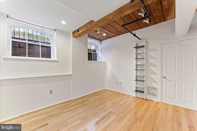 basement with wood ceiling, a healthy amount of sunlight, and wood-type flooring