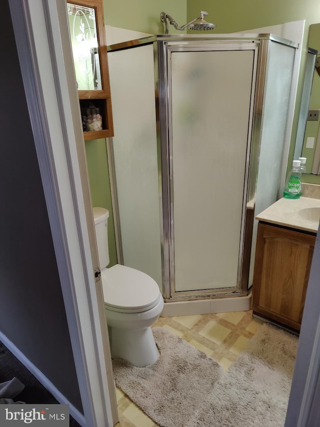 bathroom with vanity, toilet, and a shower with door