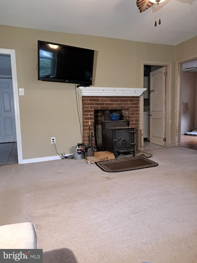 unfurnished living room with carpet flooring, a wood stove, and ceiling fan