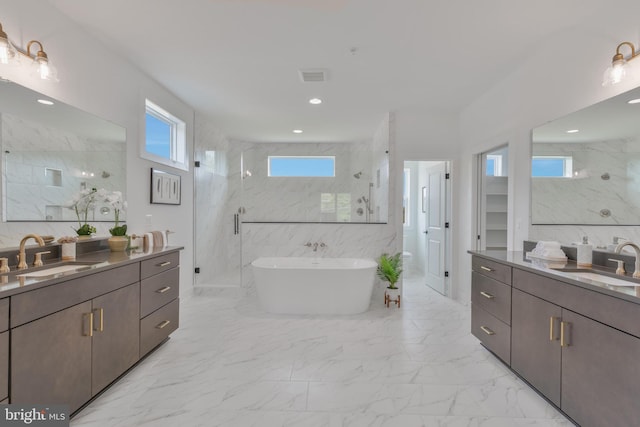 full bath featuring a marble finish shower, marble finish flooring, two vanities, a freestanding tub, and recessed lighting