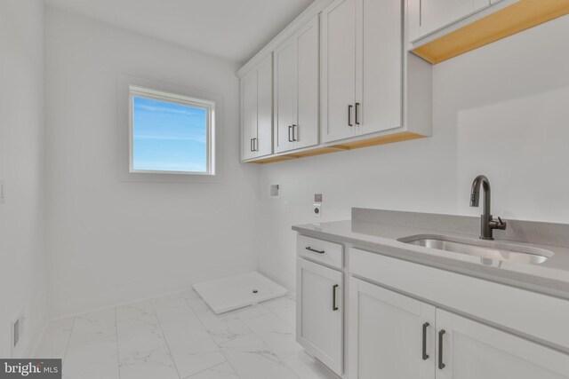 laundry room featuring hookup for an electric dryer, washer hookup, light marble finish flooring, cabinet space, and baseboards
