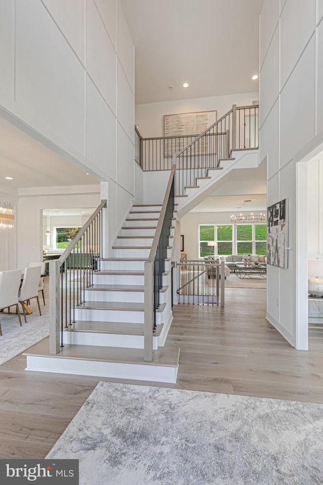 staircase featuring a towering ceiling and hardwood / wood-style flooring