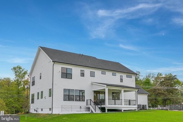 rear view of house with cooling unit, a lawn, and a porch