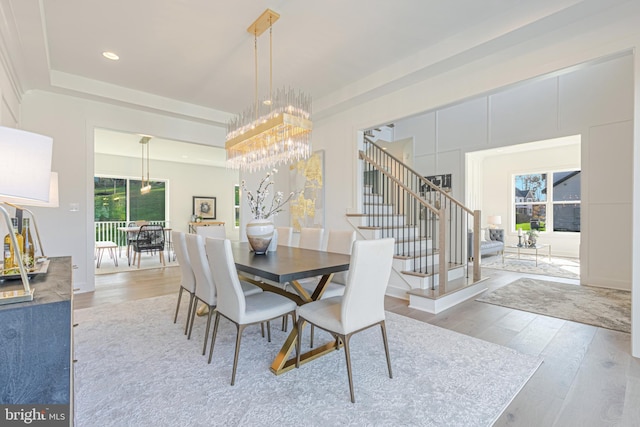 dining space with wood finished floors, stairs, a chandelier, recessed lighting, and a raised ceiling
