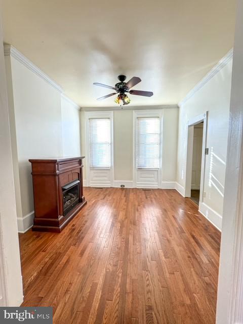 unfurnished living room with ornamental molding, light wood-type flooring, and ceiling fan