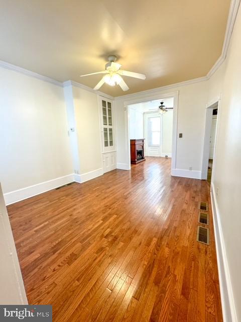 unfurnished living room with hardwood / wood-style floors, ceiling fan, and ornamental molding