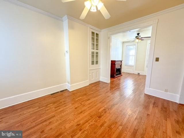 spare room with hardwood / wood-style floors, ceiling fan, and crown molding