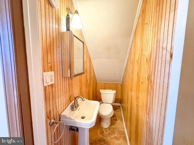 bathroom with tile patterned floors, wooden walls, and toilet