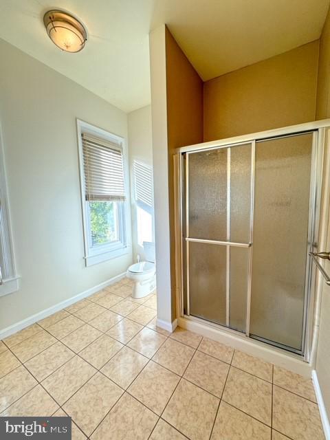 bathroom featuring walk in shower, tile patterned flooring, and toilet