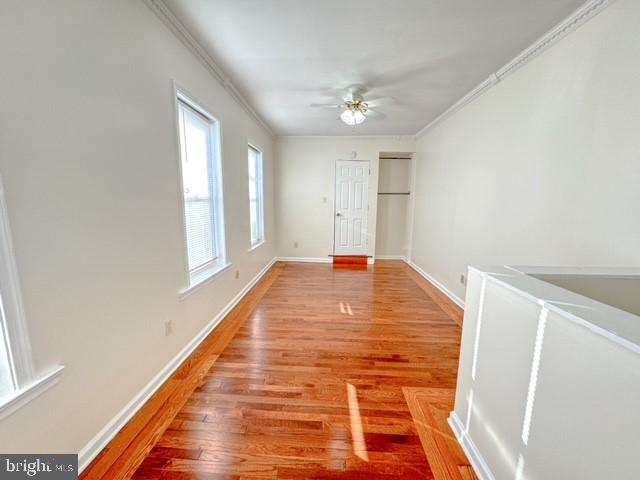 hall with light wood-type flooring and crown molding