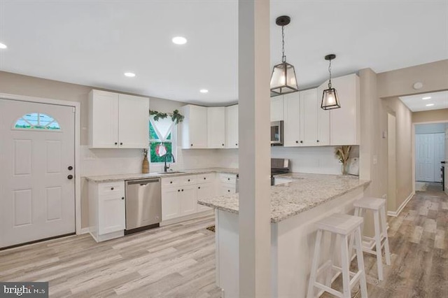 kitchen with white cabinets, a kitchen bar, stainless steel appliances, and kitchen peninsula