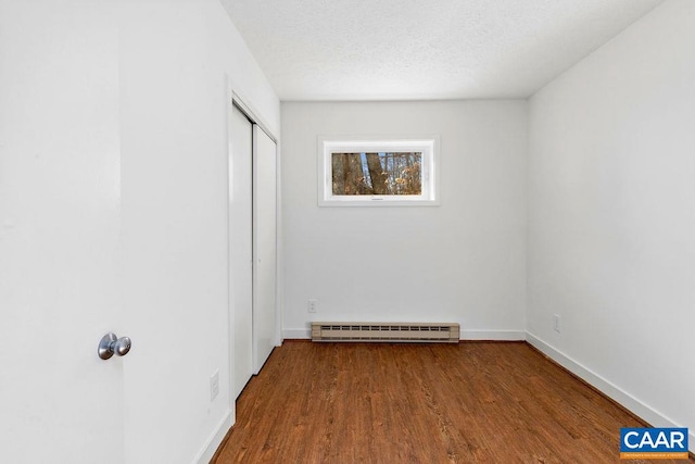 unfurnished bedroom featuring a textured ceiling, a closet, hardwood / wood-style floors, and a baseboard radiator