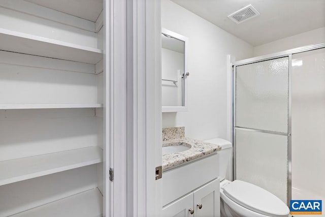 bathroom featuring vanity, toilet, and a shower with door