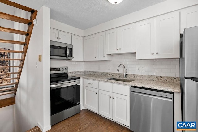 kitchen featuring stainless steel appliances, dark hardwood / wood-style flooring, white cabinets, decorative backsplash, and sink