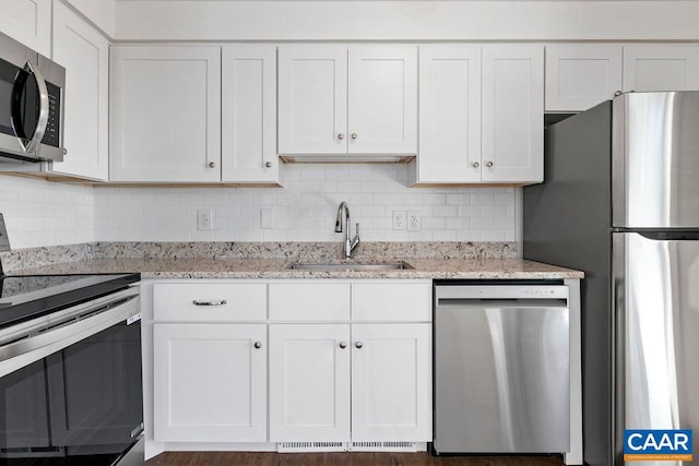 kitchen with sink, appliances with stainless steel finishes, tasteful backsplash, light stone countertops, and white cabinets