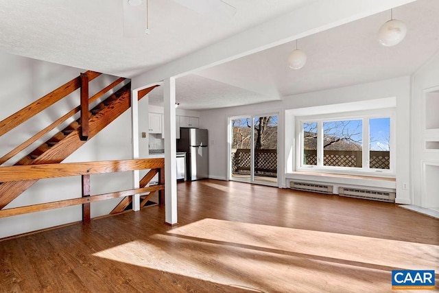 unfurnished living room with baseboard heating and dark hardwood / wood-style flooring