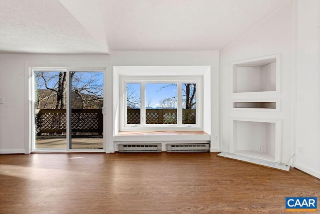 unfurnished living room featuring a wealth of natural light, a textured ceiling, and hardwood / wood-style flooring