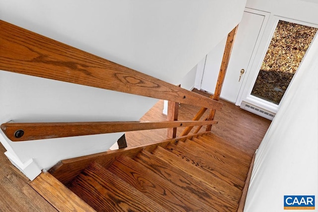 stairs featuring hardwood / wood-style floors and a baseboard heating unit